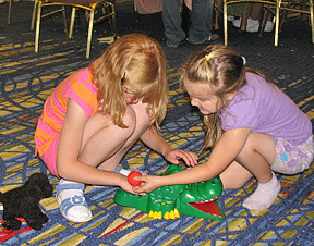 Emma McCready (OR), on the left, and Anna Walker (PA) figure out together how to play with a toy at the 2007 NFB Camp. When blind kids have access to well-designed, accessible toys and games, they don�t need adults hovering over them all the time�they can figure it out themselves.