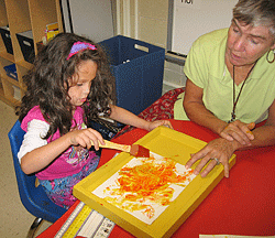 Kendra works on an art project while Dr. Laurel Hudson, her TVI, watches.