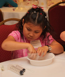 Involved in a chemistry experiment, Ashleya Chamberlain sits with her hands in a bowl.