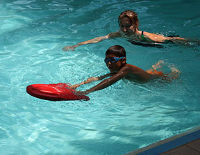 student practices his kick in the pool while holding a float at arm&rsquo;s length. Check out 'Picturing Convention.'