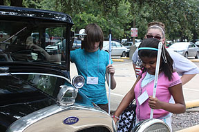 Two young girls examine an antique Ford