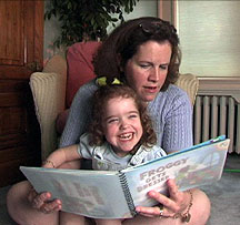 Mother with a laughing baby girl on her lap; both mother and child enjoy reading Froggy Gets Dressed.