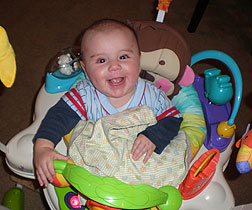 Gavin bounces in a jumper swing with toys attached all around the tray.