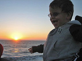 Sunrise on the beach illuminates a laughing child. 