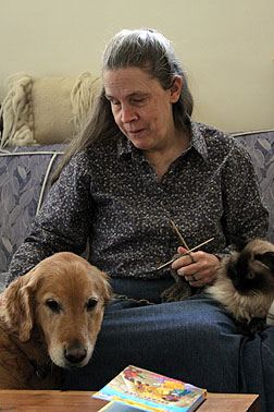 Sue with her guide dog beside her and her cat in her lap.