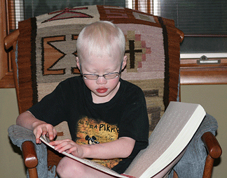 Matthew reads Braille, sitting upright and relaxed.