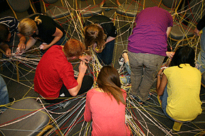 Students untangle a spiderweb of yarn.