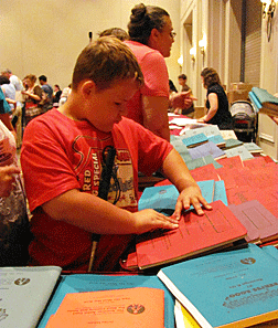 Boy intently reads the cover of a Braille book