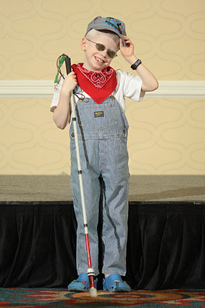 Dressed in a train engineer's outfit, Daniel Kay stands in front of the runway.