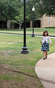 Abby Duffy walking down a sidewalk with her cane