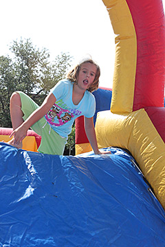Girl poised at the top of the slide in the bounce house