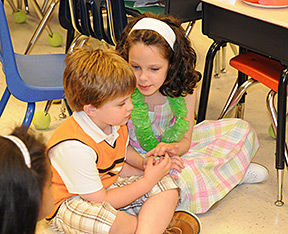 Kendra and a classmate seated on the floor at a school party