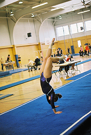 Rose Sloan on her hands on the mat with her feet in the air.