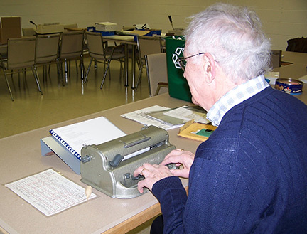 A volunteer uses a Perkins Brailler to transcribe a book.