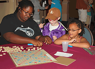Emerie Mitchell-Butler and another child play Braille Scrabble in Kids Camp.