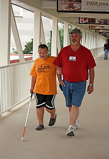 A father and son walk together, using human guide technique.