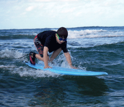 Vejas Vasiliauskas crouches on a surfboard.
