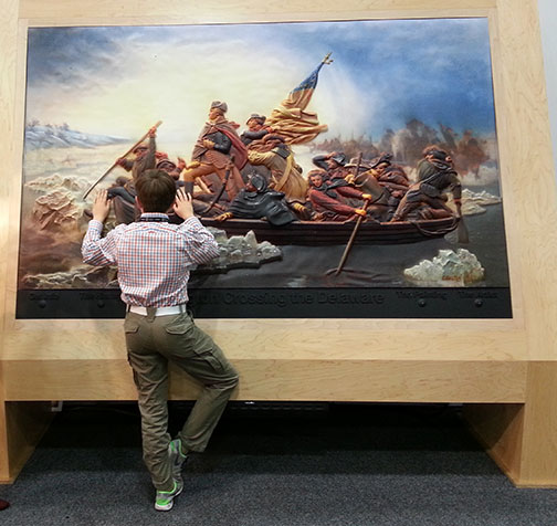 A boy examines a 3D photo of Washington Crossing the Delaware.