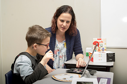 Using Osmo tiles, a boy adds toppings to a pizza.