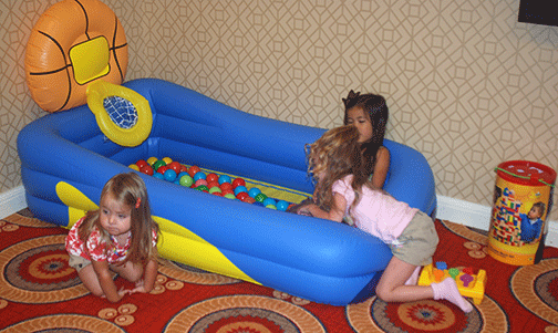 Tres ni&ntilde;as juegan en una piscina inflable de pelotas.