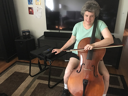 With her cello in front of her, Leslie Hamric reads music from her Braille device.