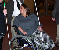Treva Olivero sits in her wheelchair holding her long white cane.