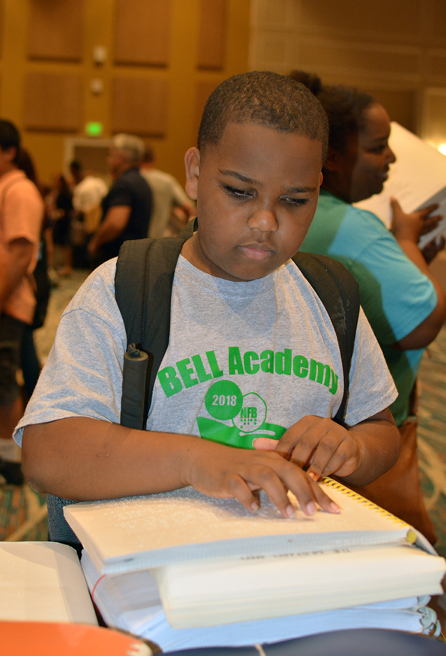 Kyle Anthony reads from a Braille book.