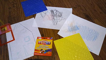 This photo shows an assortment of items from the Tactile Art Kit and some of the drawings children have made.