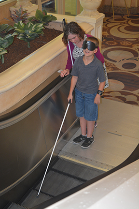 Domonique Lawless teaches Ian Oliver to use his cane on the escalator.