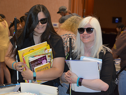 Trinda Huerta and Katie Cuppy gather armloads of books at the Braille Book Fair.