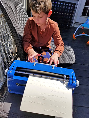 Daxton works on his Perkins Braille writer.