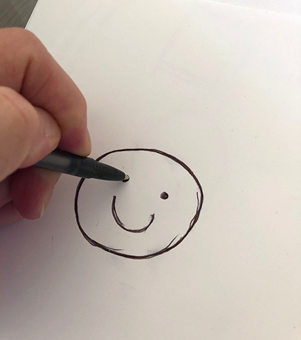 A hand draws a smiley face.
