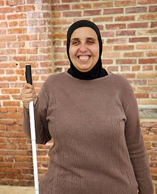 Ronza Othman smiles and holds her cane. Read her story called Living the Life I Want Because of Parental Empowerment