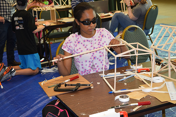 A student uses tools to build a model structure.