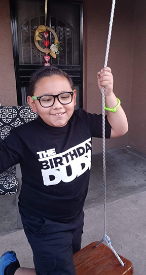 Chris Lopez plays outside on a swing.