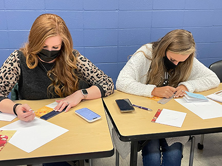 Two teachers learn to use the slate and stylus.