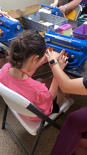 At the Louisiana NFB BELL Academy a mentor helps a student use a Perkins Braillewriter.