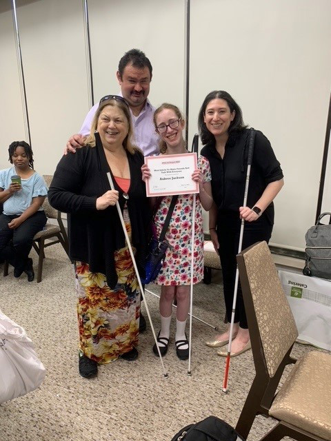 Project RISE Coordinator Joe Orozco, Curriculum Coordinator Julia Ford, and mentor Jacki Bruce stand with student Aubree Jackson. Aubree holds an award certificate. 