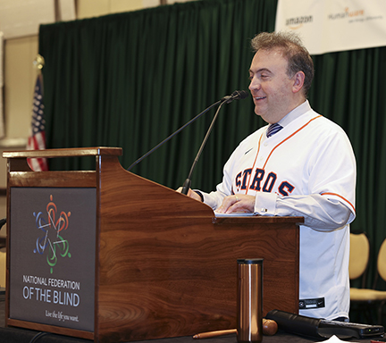 Wearing a Houston Astros jersey, NFB President Mark Riccobono leads the opening ceremony of the NFB General Sessions.