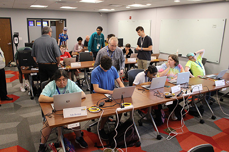 Blind students work on laptops in a classroom setting.