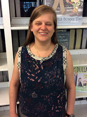 Chancey Fleet stands in front of a shelf of children&rsquo;s books.