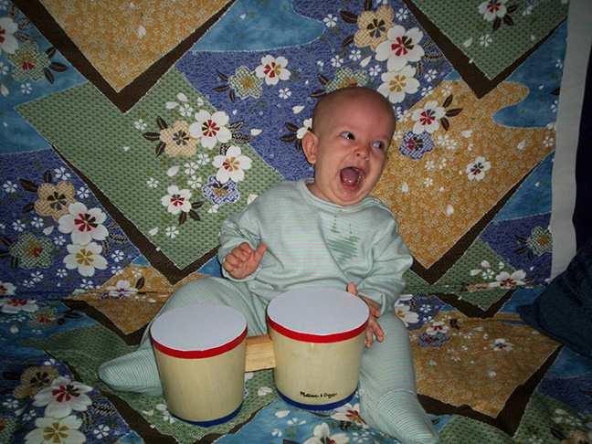 Now slightly older, Ivan plays with a set of bongos.