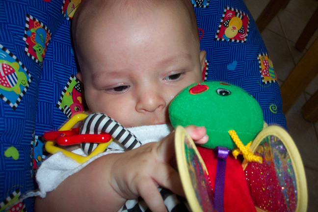 Ivan Bobnar sits in a car-seat playing with a toy bumblebee.