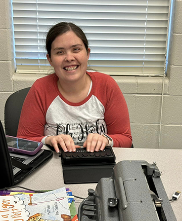 Stephanie reads from an electronic Braille device.