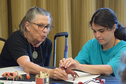 Ann Cunningham shows a horse model to a young woman who is about to try her hand at drawing.