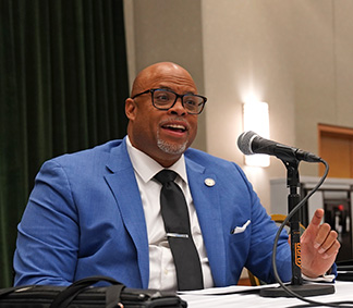 Dant&eacute; Allen sits on the stage in front of a microphone.