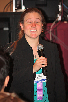 Julie Orozco stands holding a microphone.