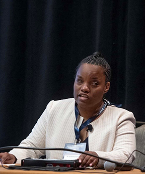 Ameenah Ghoston gives a presentation with a Braille device in front of her.