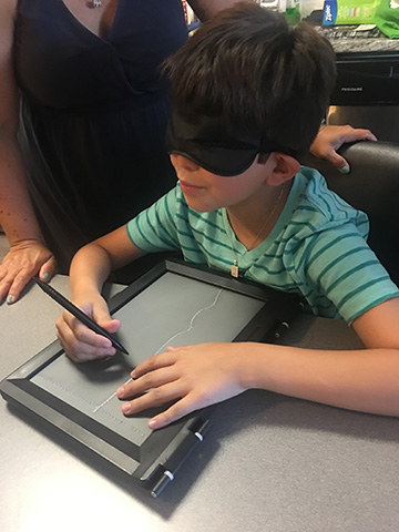 A boy uses a tactile drawing board.