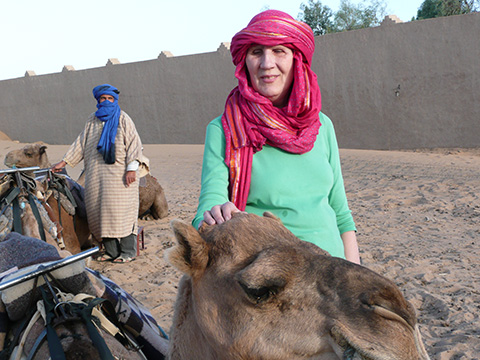 On a trip to Morocco, Deborah Kent Stein stands beside a camel.
